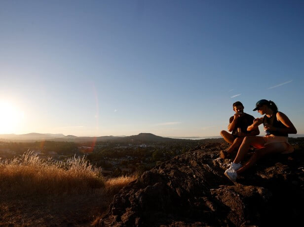 Two cross country runners resting on a hillside at sunset