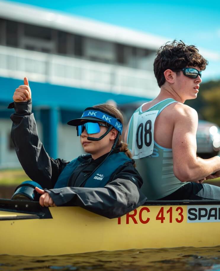 A coxswain with a megaphone beside a rower in a racing shell